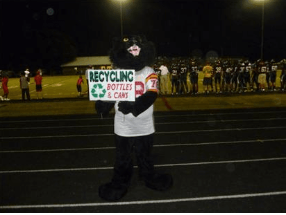 High School Mascot poses with Recycle Cans and Bottles sign