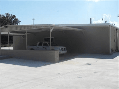 Truck parked under covered parking near entrance of hall