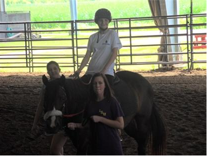 Two people pose with a child on a horse